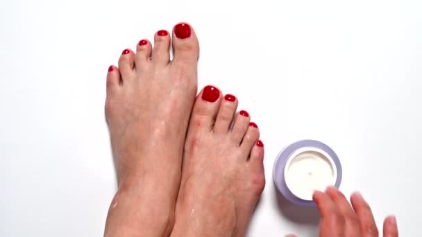 The girl is rubbing cream on her feet with problem areas of the skin - Materiał filmowy, wideo