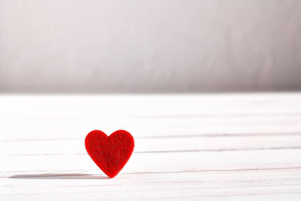 Red woolen heart on white wooden background. Valentine's day. Romance greeting card. Copy space. Minimalism. - Fotografie, Obrázek