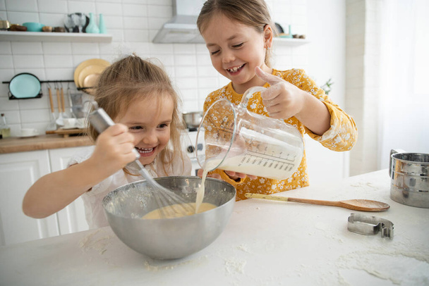 happy sisters children girls bake cookies, knead dough, play with flour and laugh in the kitchen. - Valokuva, kuva
