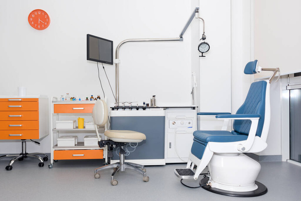 Moderne tandartspraktijk. Tandartsstoel en andere accessoires gebruikt door tandartsen. Tandartspraktijk, tandheelkundige hygiëne. Kleurrijk interieur van tandartspraktijk met stoel en gereedschap - Foto, afbeelding