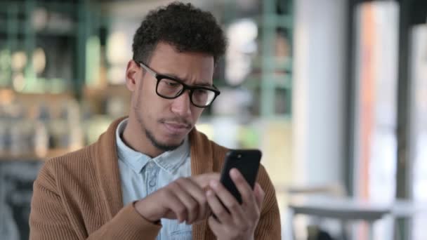 Fiatal afrikai férfi használ okostelefon, Böngészés Internet - Felvétel, videó
