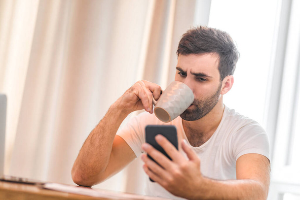 Photo of bearded man in white shirt taking a selfie with his smartphone. - Valokuva, kuva