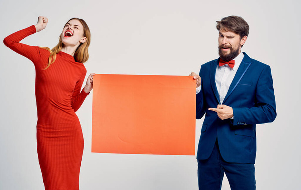 Un homme avec une feuille de papier rouge dans ses mains et une femme dans une robe affiche mocap publicité - Photo, image