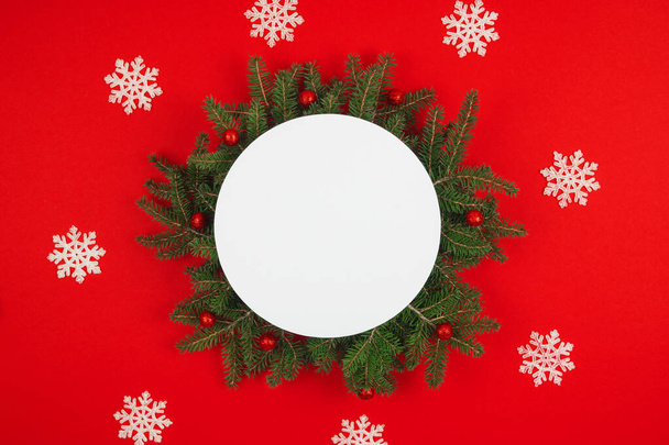 Top näkymä pyöreä joulun tausta kuusen oksat ja lumihiutaleet, koristeet punaisella taustalla. Juhlapyhien tausta. Mock up. Kopioi tilaa. - Valokuva, kuva