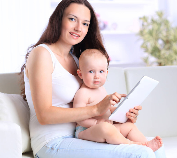 young mother with her baby looking at the screen of a digital tablet. - Photo, Image