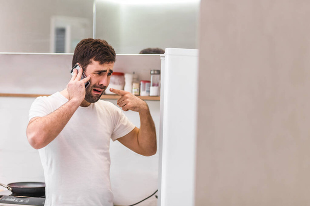 Portrét mladého muže mluvící po telefonu izolované na bílém pozadí. - Fotografie, Obrázek
