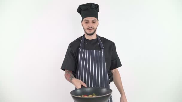 Mosolygós férfi che dobált zöldségek egy serpenyőben a kamera előtt - Felvétel, videó