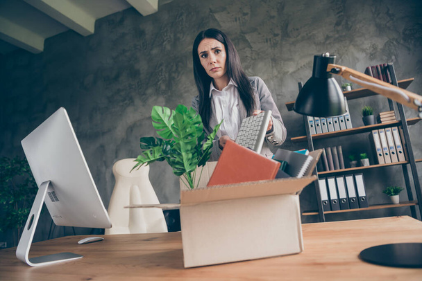 Low angle view photo of frustrated girl collar put keyboard in cardboard box quit office marketer occupation company crisis bankrupt wear blazer jacket suit in workplace workstation - Фото, зображення