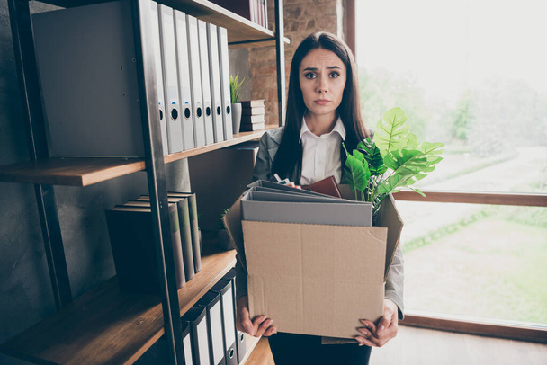 Photo of frustrated stressed depressed girl ceo expert lose job hold cardboard box with folders wear blazer jacket suit in workplace workstation - Фото, изображение
