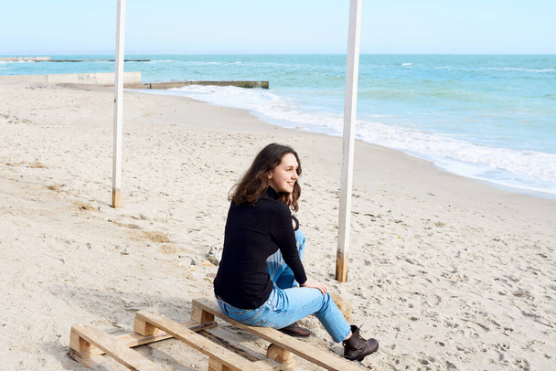 Feliz mujer sonriente relajándose junto al mar en invierno - Foto, imagen
