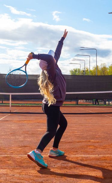 Cute blonde little girl with tennis racket and ball against sky - Photo, Image