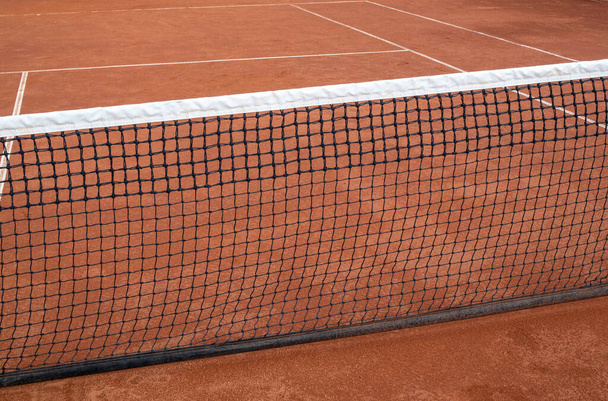 Valkoinen tennisverkko punaisella tenniskentällä. Urheilun ja toiminnan käsite - Valokuva, kuva