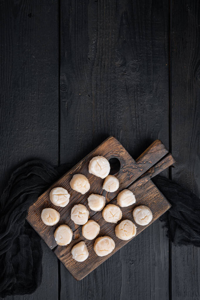Fresh raw uncooked scallops, top view, on black wooden background  with copy space - Fotografie, Obrázek