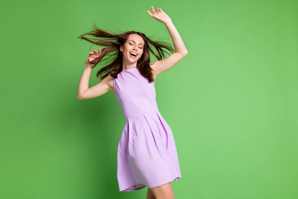 Photo of crazy pretty young lady model close eyes hands air blowing hairdo have fun relax disco queen party club discount concert wear violet dress isolated pastel green color background - Fotoğraf, Görsel