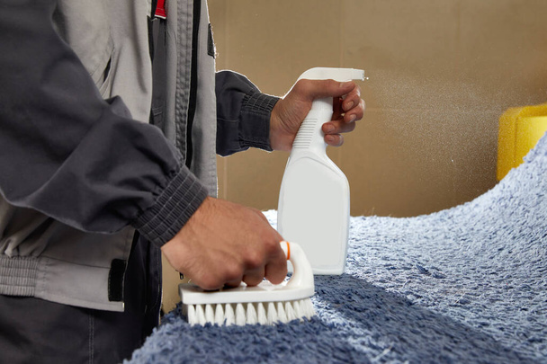 Mężczyzna przy użyciu sprayu do usuwania plamy z dywanu w usłudze czyszczenia dywanów - Zdjęcie, obraz