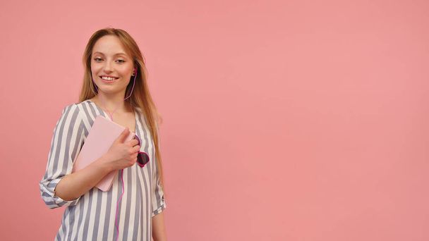 Zelfverzekerde jonge blonde vrouw met notebook geïsoleerd op roze achtergrond - Foto, afbeelding