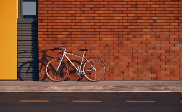 Stylish urban bicycle on sidewalk with brick wall - Фото, зображення
