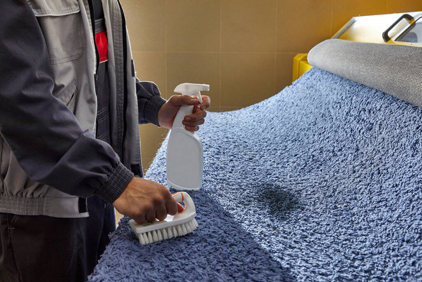 Detergente spray uomo sul tappeto grigio per rimuovere la macchia nel servizio di pulizia professionale  - Foto, immagini