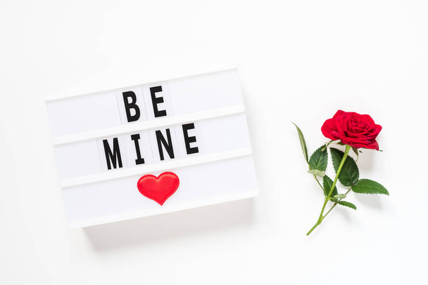Día de San Valentín, amor, concepto romántico. Flor de rosa roja fresca y texto ser mío en lightbox sobre fondo blanco. Tarjeta de felicitación. Piso tendido, vista superior. - Foto, imagen