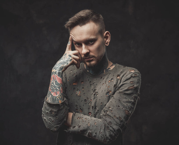 Hipster person poses in dark background with finger to his head - Photo, Image