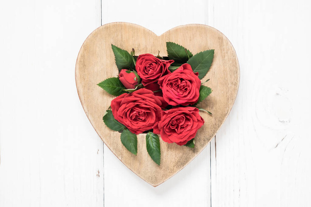 Valentine's day, love, romantic concept. Red roses and wooden heart on white background. Flat lay, top view, copy space. - Zdjęcie, obraz