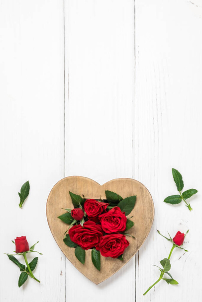 Valentine's day, love, romantic concept. Red roses and wooden heart on white background. Flat lay, top view, copy space. - Foto, Imagem