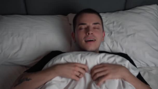 Rustige glimlachende knappe man gaat slapen in comfortabele gezellige frisse bed genieten van gezonde goede nachtrust. - Video