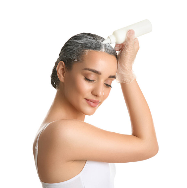 Mulher jovem aplicando tintura em cabelos contra fundo branco - Foto, Imagem