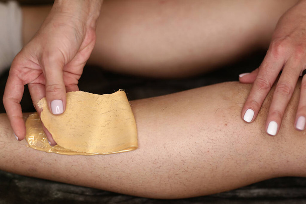 косметические руки сделать процедуру депиляции на ногах женщины с воском крупным планом фото - Фото, изображение