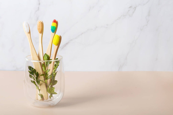 bamboo toothbrushes on a beige background in a glass glass. Pride Month - Bamboo Rainbow Dental Toothbrush - Love Your Teeth Concept - Brush Your Teeth - Photo, Image