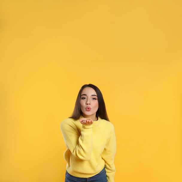 Beautiful young woman wearing warm sweater on yellow background. Space for text - Foto, Imagen