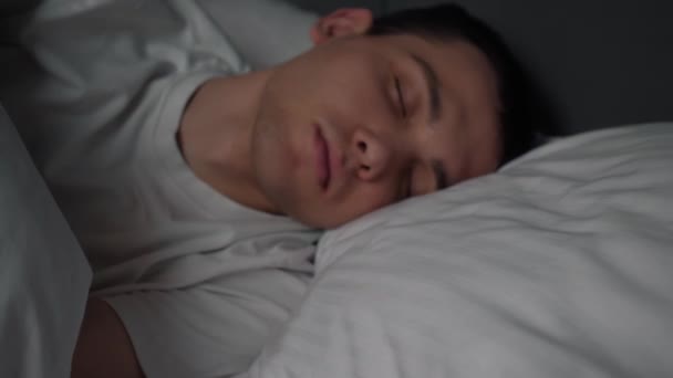 Tranquilo hombre guapo se va a dormir en una cómoda y acogedora cama fresca disfrutando de una buena siesta de sueño saludable. - Metraje, vídeo