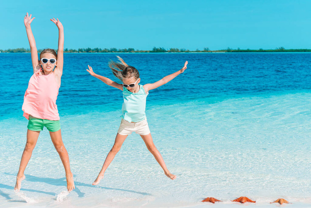 Adorable little girls have a lot of fun on the beach. - Фото, зображення