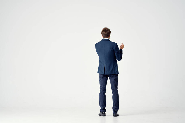 Rückansicht eines Mannes im Anzug auf hellem Hintergrund, der mit seinen Händen in vollem Wuchs gestikuliert - Foto, Bild