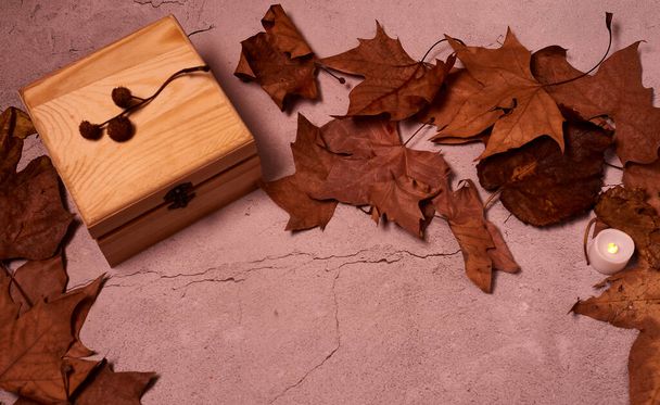 Wooden box on stone floor and autumn leaves, closed box, front view, - Foto, immagini