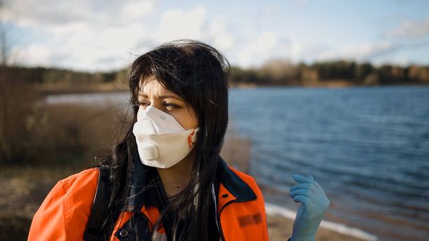 Un paramédico femenino serio gira la cabeza y te mira cerca del lago azul - Foto, Imagen