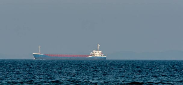 Μπλε φορτηγό πλοίο πλέει στον ωκεανό από απόσταση. . Υψηλής ποιότητας φωτογραφία - Φωτογραφία, εικόνα
