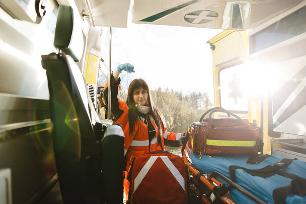 Femme ambulancier saisit grand sac d'équipement et laisse véhicule d'urgence - Photo, image
