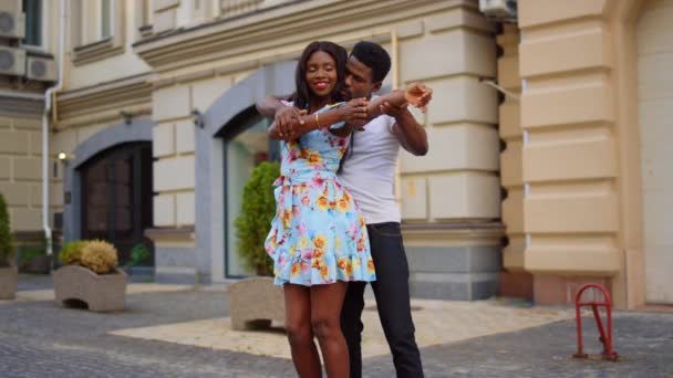 屋外で踊る魅力的なアフリカのカップル。男と女が路上で動く - 映像、動画