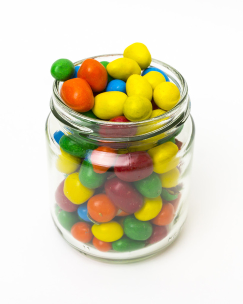Bonbons colorés isolés dans un bocal ouvert sur fond blanc
. - Photo, image