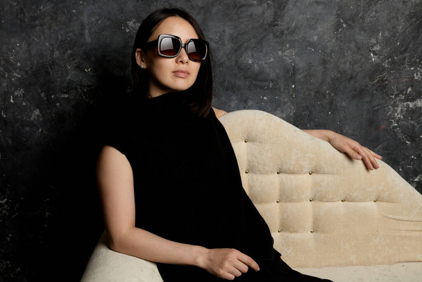 Beautiful korean woman dressed in black dress sitting on sofa - Foto, Bild