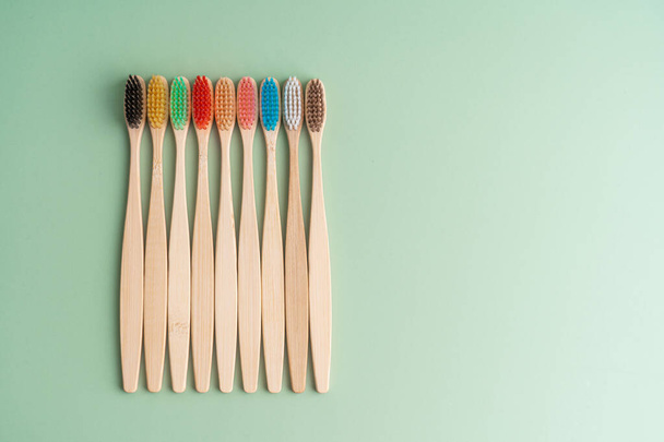 Un conjunto de cepillos de dientes antibacterianos ecológicos hechos de madera de bambú sobre un fondo verde claro. Tendencias del cuidado ambiental. - Foto, imagen