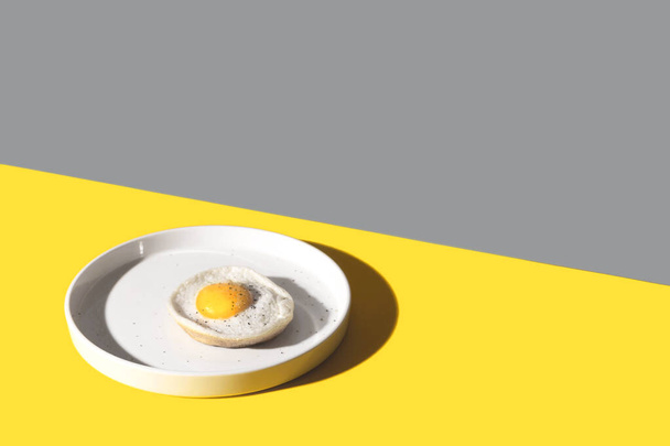 Τηγανητό αυγό σε λευκό πιάτο Χρώμα του έτους 2021 - Φωτογραφία, εικόνα