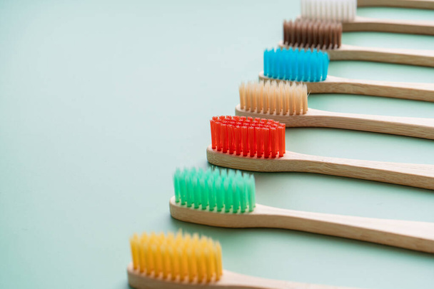 A set of Eco-friendly antibacterial toothbrushes made of bamboo wood on a light green background. Environmental care trends. - Foto, Imagem