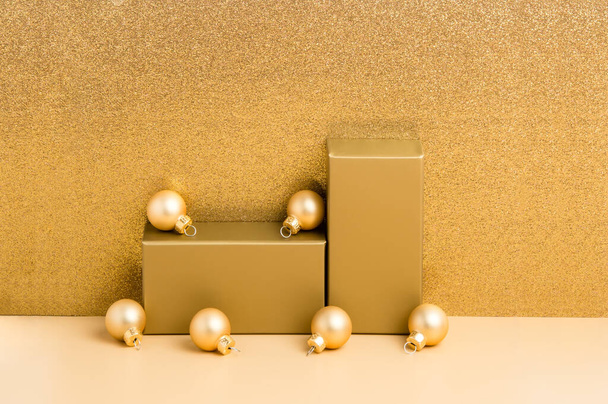 Χρυσό βάθρο για παρουσίαση προϊόντων σε μπεζ και πολυτελές glitter φόντο, χρυσές χριστουγεννιάτικες μπάλες. Πρωτοχρονιάτικος εορταστικός σχεδιασμός διακοπών ή μακιγιάρισμα για τοποθέτηση πακέτων, πώληση προώθησης, επίδειξη καλλυντικών - Φωτογραφία, εικόνα