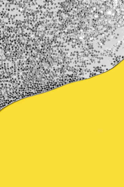 átlátszó folyadék ezüst csillámporral, pasztell sárga háttérrel - Fotó, kép