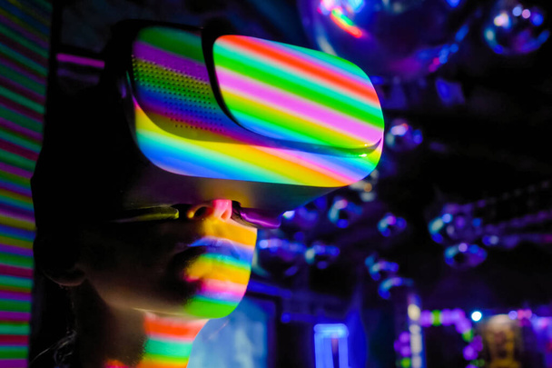 Mujer joven usando auriculares de realidad virtual en la exposición interactiva oscura VR - Foto, Imagen