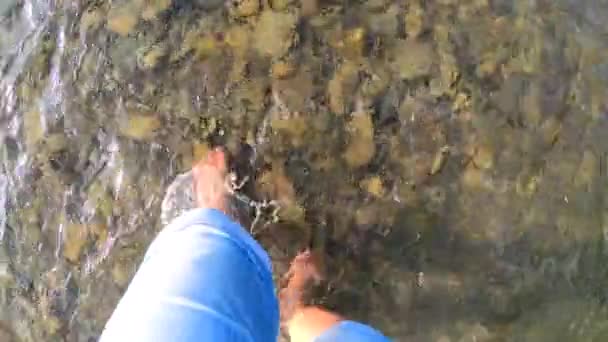 Chica caminando descalza sobre piedras de río poco profundo primer plano, día de verano soleado - Metraje, vídeo