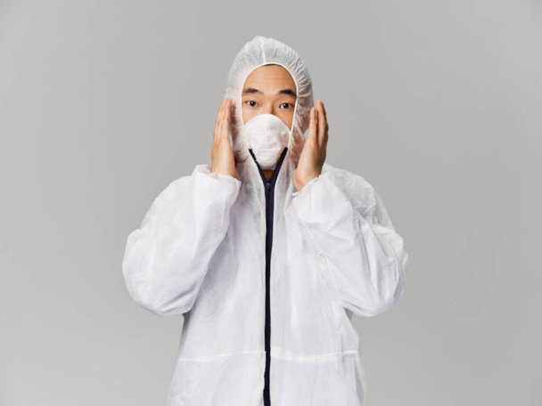 homem de aparência asiática em roupas médicas mãos perto de proteção facial - Foto, Imagem