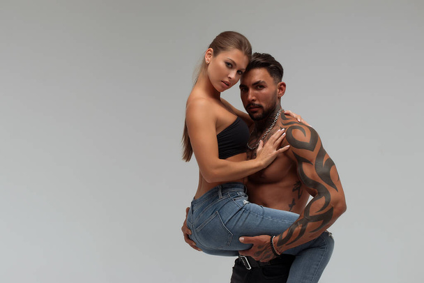 Strong shirtless male embracing and covering breast of attractive topless female on gray background - Foto, Bild